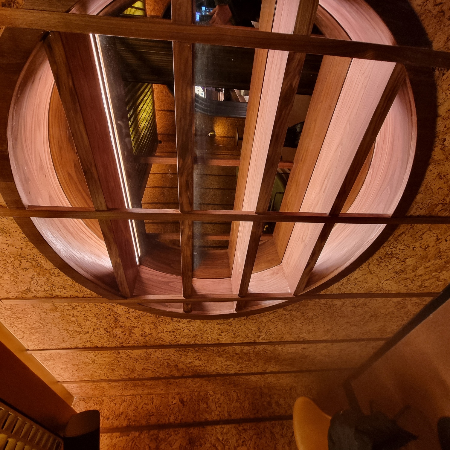 Finished circular walnut shelving with reflective glass and concealed lighting