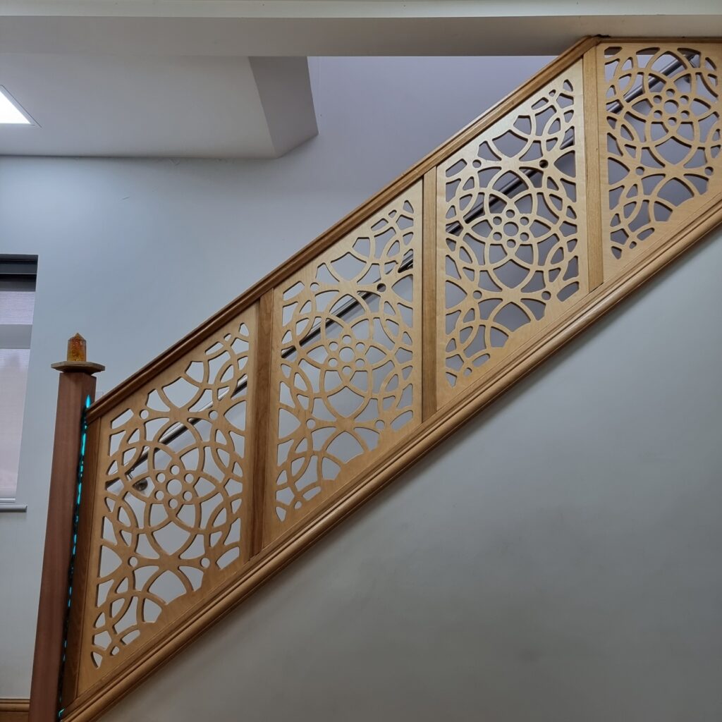 CNC-cut staircase balustrade with circular fretwork in birch plywood, oak frame, oak handrail and illuminated sapele newel post – bespoke joinery Kent