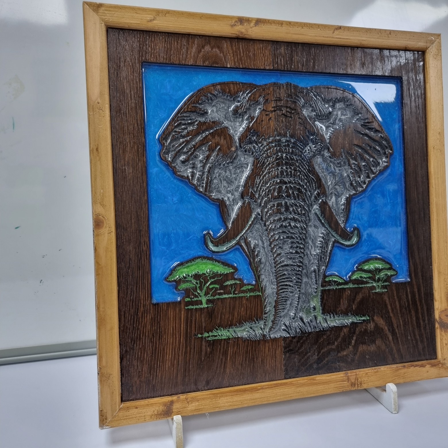 Angled view of bull elephant resin wall art with blue sky and green resin details.