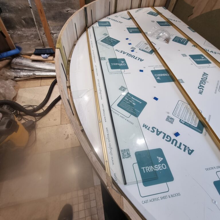 Workshop fabrication of curved champagne display structure with LED integration and glass channel joinery by Kustom Made Ltd